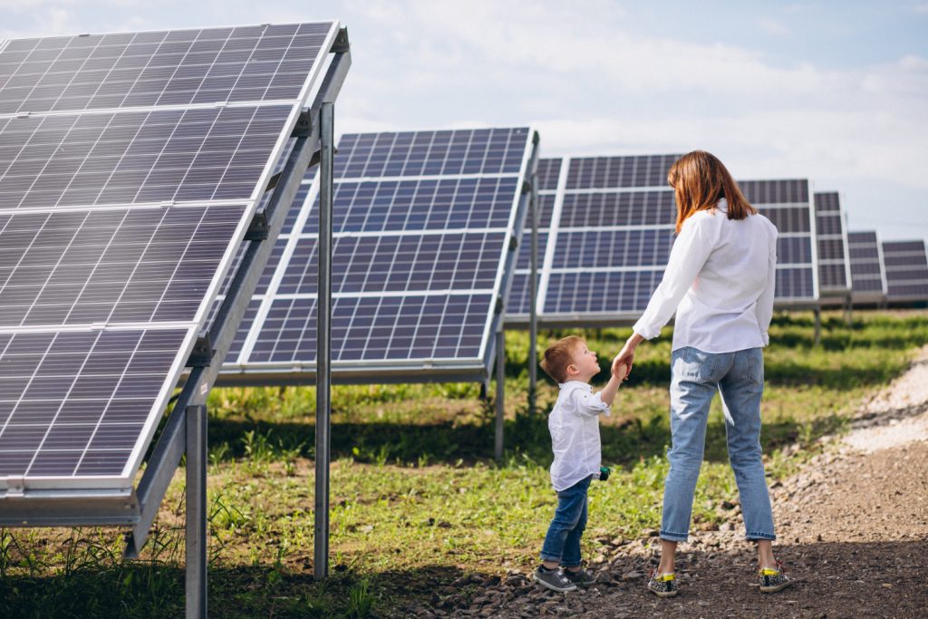 a mother with her son stands near a row of solar panels