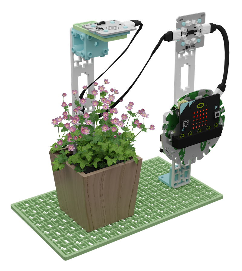 A 3D rendering of an educational robotic setup observing a flowerbed. On the left, a sensor mounted on a vertical stand hovers over pink flowers with green foliage in a wooden planter. On the right, a robotic arm equipped with a LED and micro:bit controller is angled towards the plants, presumably to interact with or monitor them. The entire assembly is positioned on a grid-like green baseplate, suggesting a modular design for educational purposes.