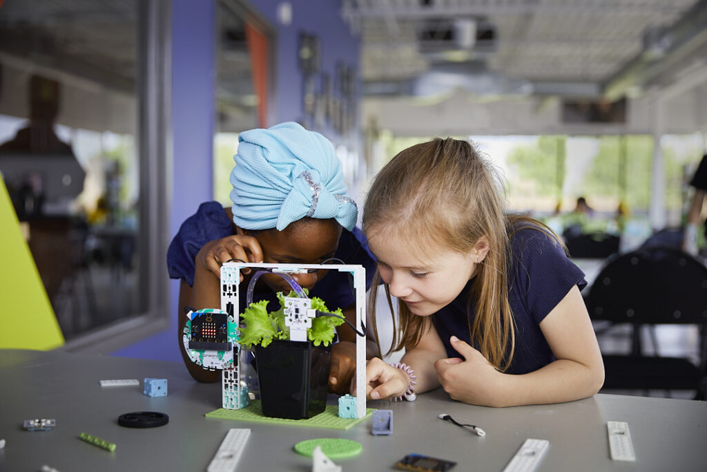 Two female students looking closely at the micro:bit smart farming project from the Climate Action Kit
