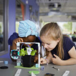 Two female students looking closely at the micro:bit smart farming project from the Climate Action Kit