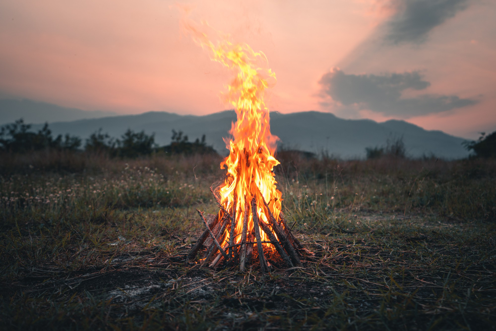 Large campfire in a field at sunset.