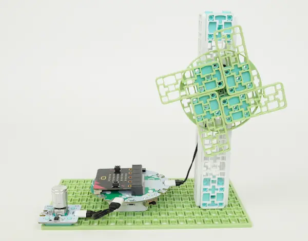 A looping GIF of a wind turbine model in action. The small turbine spins rapidly as a dial is turned.