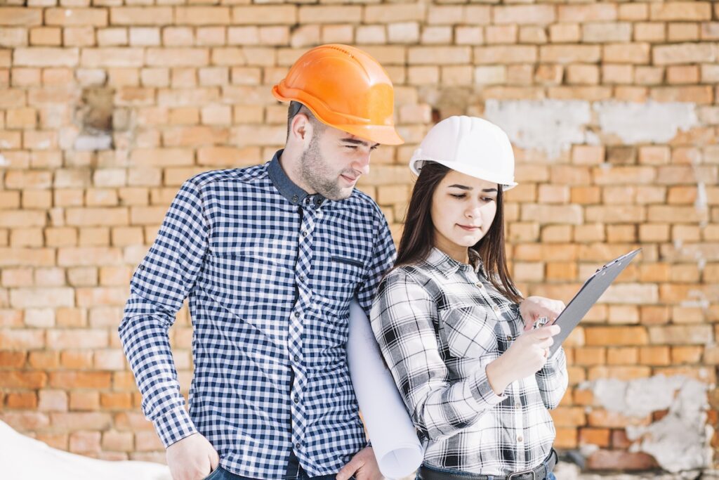 Two people in a hard hat looking at a clipboard