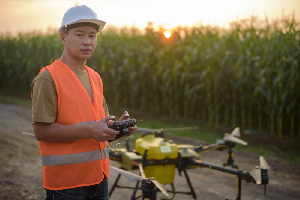 Drone pilot stand in front of a person-sized drone beside a corn field.