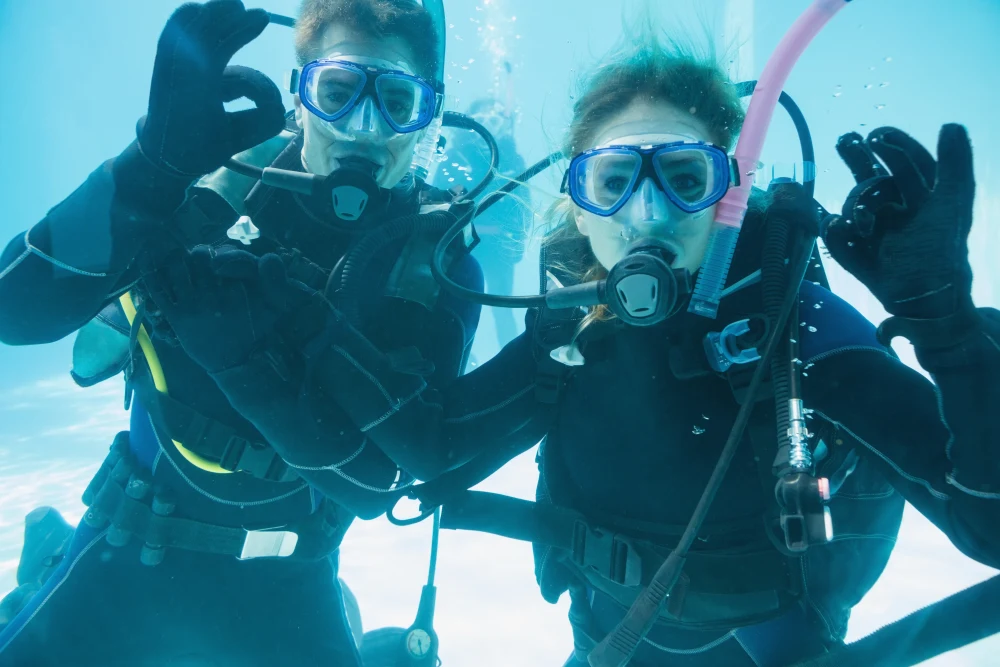 Two marine biologists looking at the camera underwater with full scuba gear.