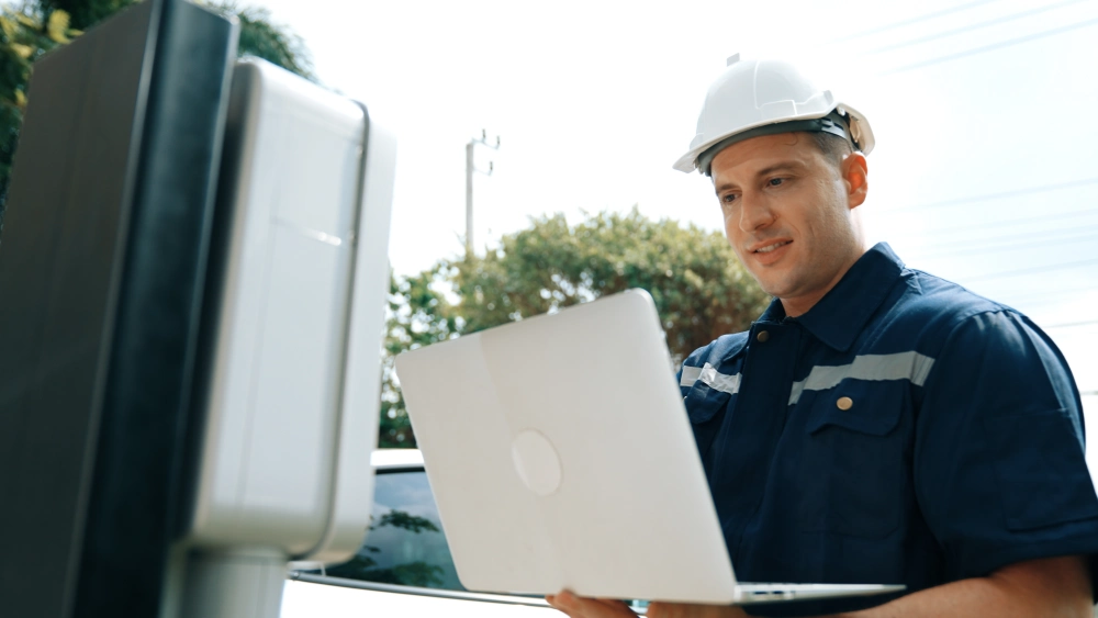 Technician working on a laptop in front of equipment.
