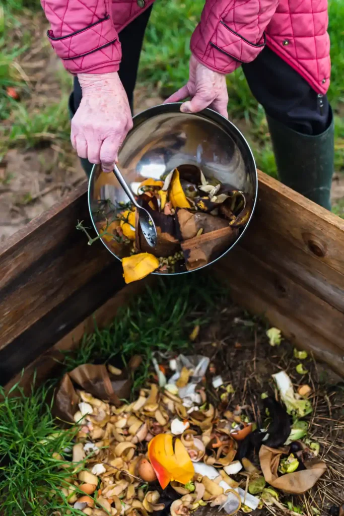 Person scrapping food scraps into a compost.