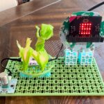 Real-world build of Forward Education's coral reef model. The build uses the kit's building blocks to create a platform for the LED light. Then, tissue paper is wrapped around the light to represent the reef. The pink of the light still shines through the tissue paper/coral.