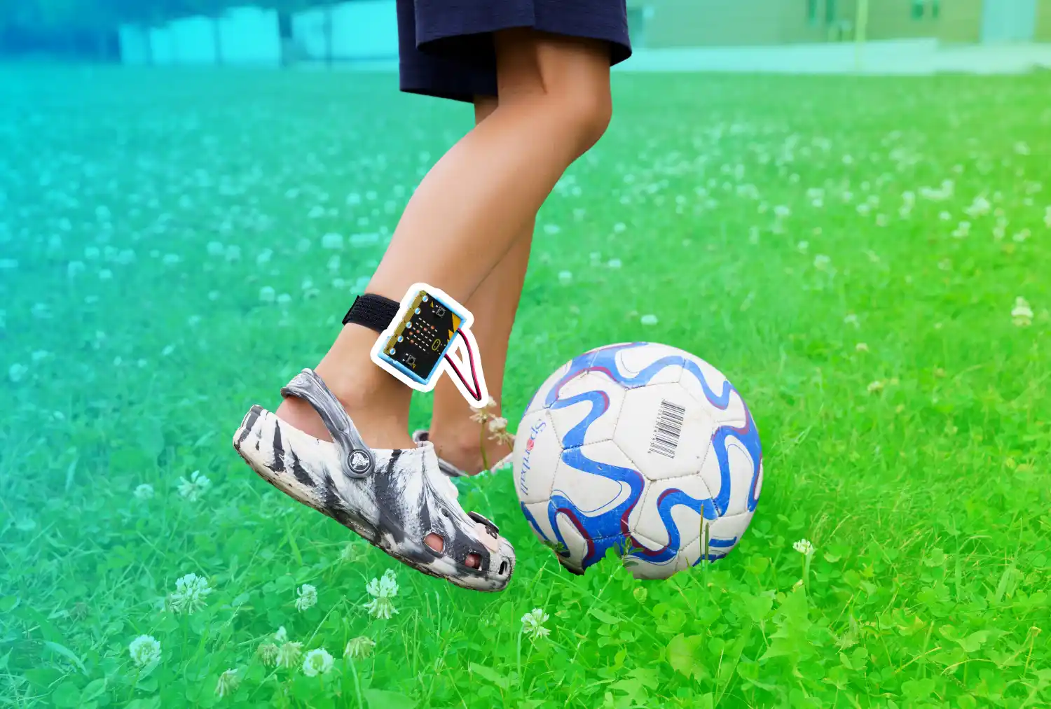 Someone kicking a soccer ball with a CHARGE power pack and micro:bit on their kicking leg. A blue to green gradient is overlaid behind the micro:bit which has a white boarder around it.