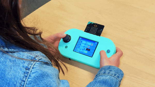 A child writes a MicroCode program on the CodeCTRL. They are using the joystick and buttons to navigate the interface.