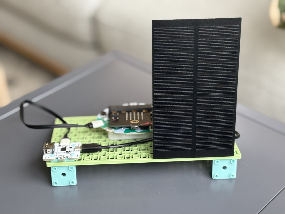 A data logging setup with a micro:bit and a small solar panel is assembled on a green building block base.