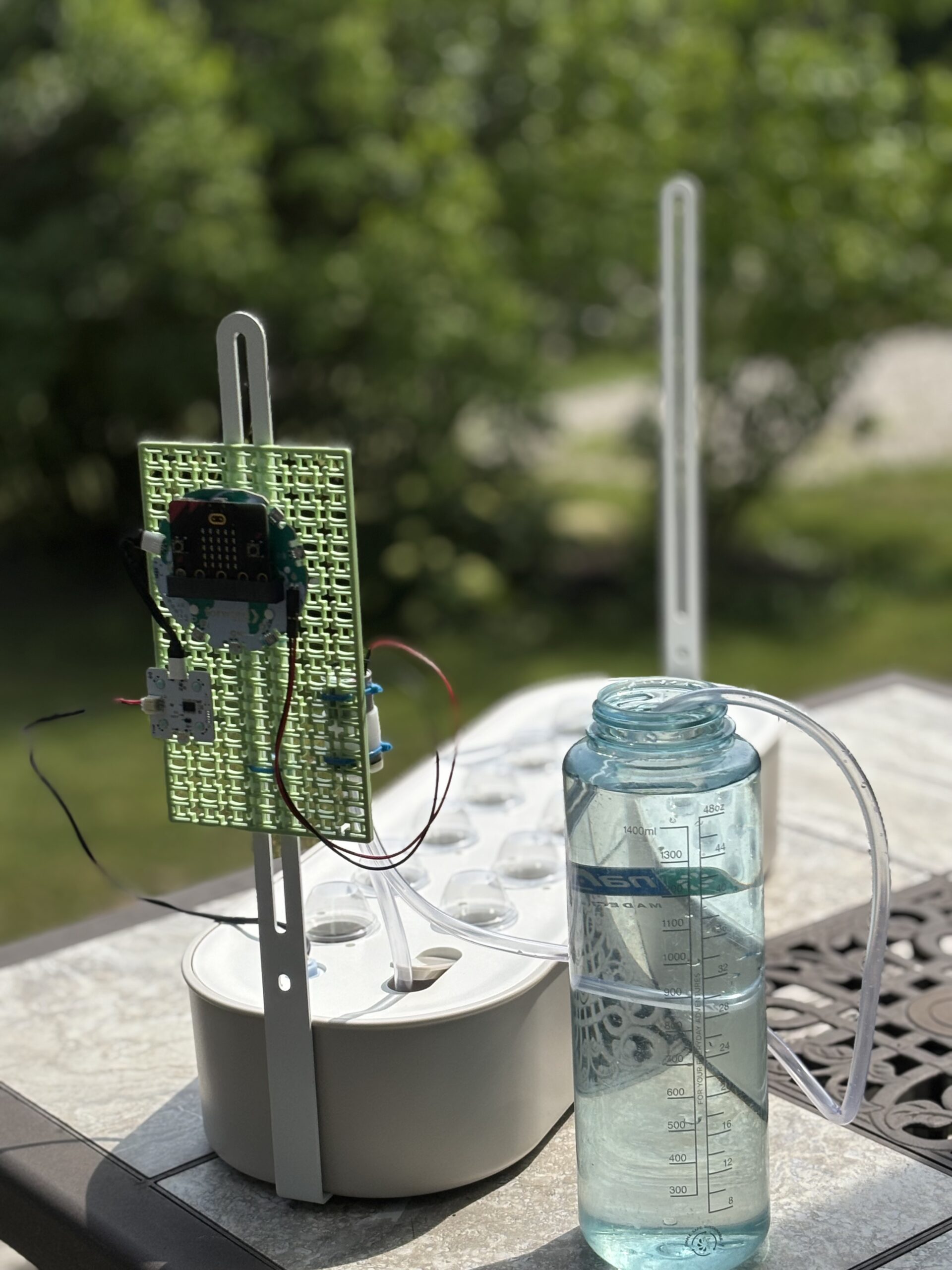 A close-up shot shows a micro:bit and various sensor boards attached to a green grid, connected with wires, all mounted on a hydroponics kit.