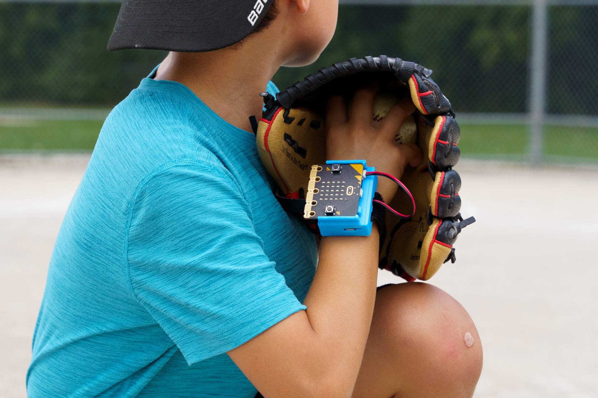 Close-up of a child preparing to throw a baseball. They have a micro:bit strapped to their wrist.